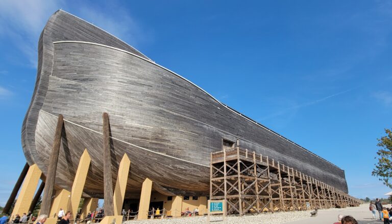 An ark is shown in a desert setting. It is in the process of being built.