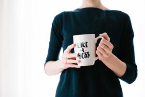 Woman in a black sweater holding a mug with the words "like a boss" printed on it.